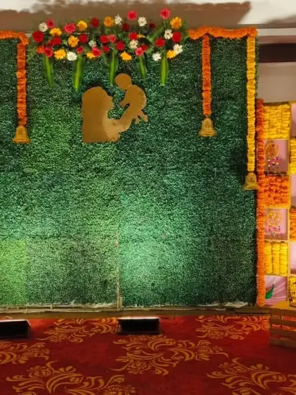 I create vibrant, traditional backdrops for ceremonies like baby showers. This design uses a natural green grass wall as a base, with a checkerboard pattern of fresh marigold flowers and a mother-child silhouette.