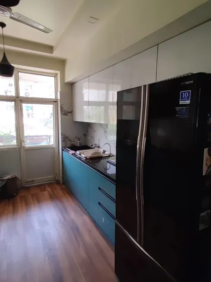 This is a great example of an efficient parallel kitchen layout, perfect for many apartments in Noida. We combined a bold ocean blue laminate on the bottom cabinets with clean, white upper cabinets. This two-tone approach makes the space feel larger while adding a splash of color. The design includes a tall unit to seamlessly integrate the refrigerator.