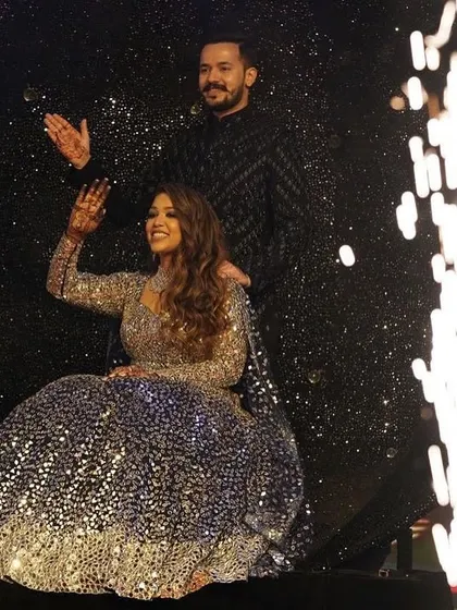 A close-up of the couple's grand entry from a sparkling sphere prop. The cold pyro adds a touch of glamour, highlighting the bride's wave to the cheering crowd.
