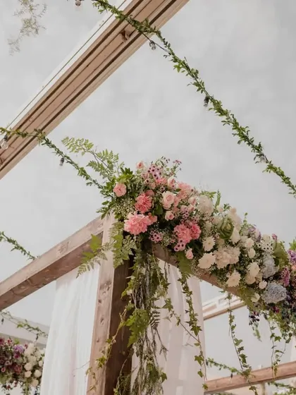 A closer look at the rustic floral decor on the mandap, with lush greenery and pastel flowers creating a natural and romantic vibe against the open sky.