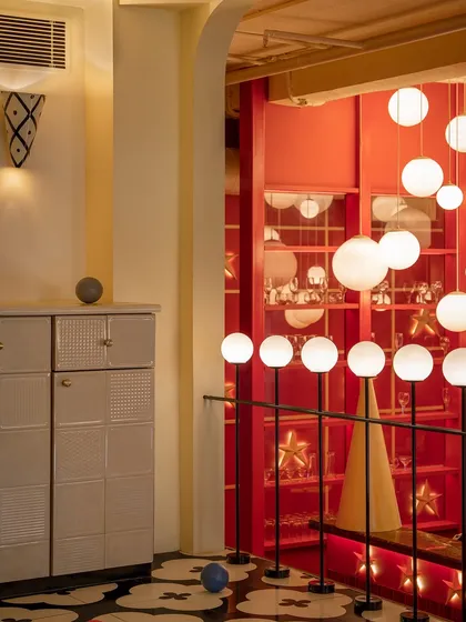 Another view of the playful details at Masala, where custom cabinetry with textured fronts stands against a backdrop of glowing red shelves. Every element is designed to contribute to a rich, layered sensory experience.