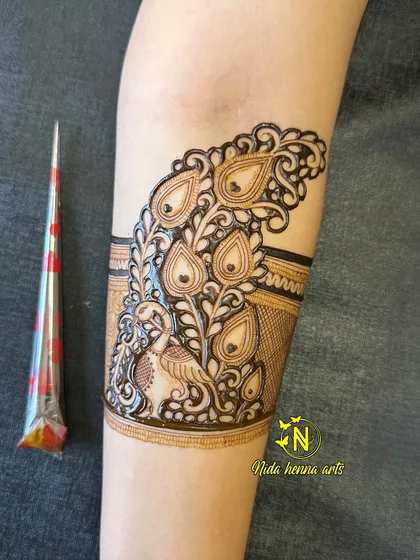 This shows the peacock cuff band on the upper arm, created with fine lines and detailed shading. I often use a henna cone to show the scale and freshness of the paste.