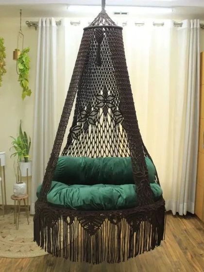 A single seater swing in dark brown with a green cushion. This combination is perfect for creating a natural, earthy vibe in your home.