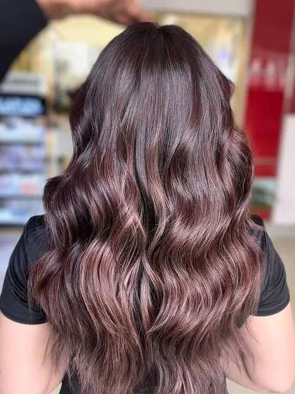 A close-up of a warm chocolate brunette balayage. You can see the seamless blend of darker roots into lighter, warmer ends, creating a beautiful, sun-kissed effect that looks natural and sophisticated.