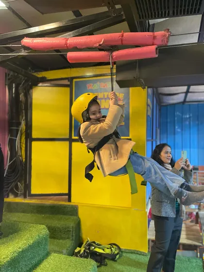 A young thrill-seeker enjoying our indoor zip-line. You can see the excitement on her face as she glides through the air, a highlight of any visit to our play zone.
