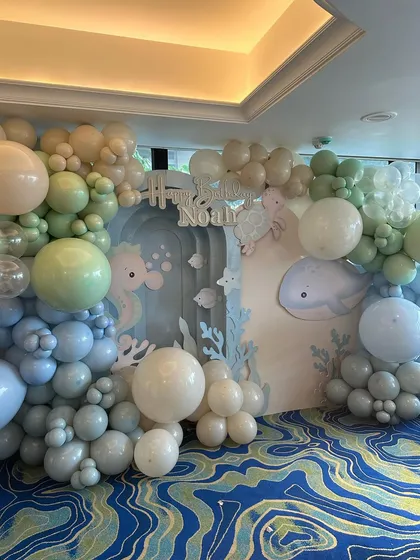 The full view of Noah's "ONEder of the Sea" party backdrop, featuring organic balloon garlands that mimic ocean waves and cute sea creature cutouts.