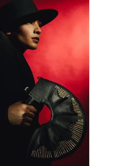 A profile shot from 'Levels of Power,' highlighting the model's strong jawline and the unique shape of the handbag. The smoky red atmosphere adds to the noir feel.