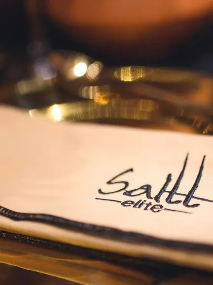 A close-up of our custom 'Saltt Elite' napkin resting on a golden plate. It's these small, branded touches that contribute to a cohesive and high-end event experience.