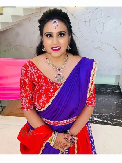 A full portrait of our client wearing her stunning red and purple half-saree, a perfect choice for a wedding or festive celebration.