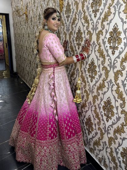 A full-length shot showing the stunning ombre effect of her lehenga. The hairstyle is a beautiful, intricate braid that complements the entire look.