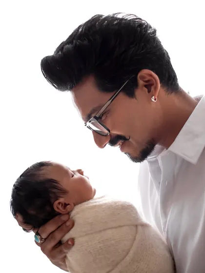 Haarsh Limbachiyaa looks lovingly at his newborn son Laksh. This portrait captures the pride and joy of a new father.