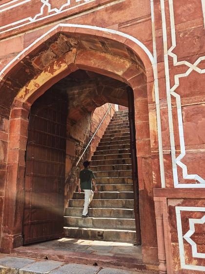 Ascending the stone steps inside Humayun's Tomb in Delhi, with the light filtering in from the arched doorway.