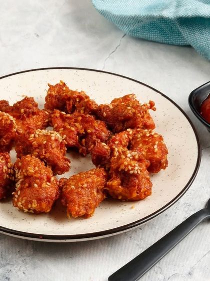 Another view of our bite-sized Popcorn Chicken, showcasing the crispy coating and sesame seed garnish.