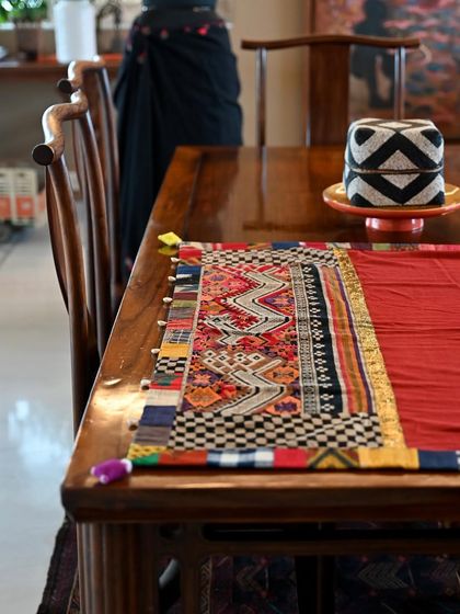 The wrap displayed on a table, allowing a clear view of the complex Naga motif woven into the vintage Laotian silk. The border is a handmade lace trim created from salvaged scraps.