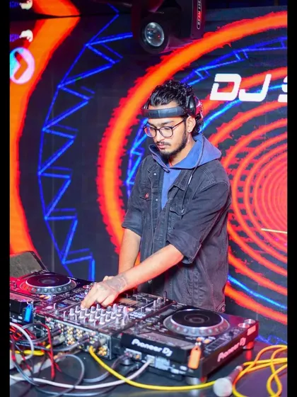 In front of a mesmerizing LED backdrop, I'm mixing tracks for a high-energy crowd. The visual setup is a key part of the experience I provide.