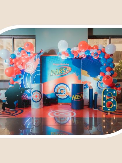This Nerf-themed stage setup for Darsh's 6th birthday is ready for action, complete with a custom backdrop, balloon arches, and a light-up number six.