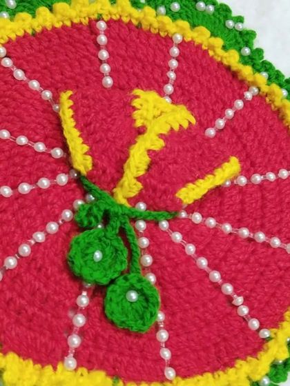 A bright and fruity design, this red woolen dress is decorated with yellow trim and a crochet bunch of green cherries. The dress is also lined with pearls.