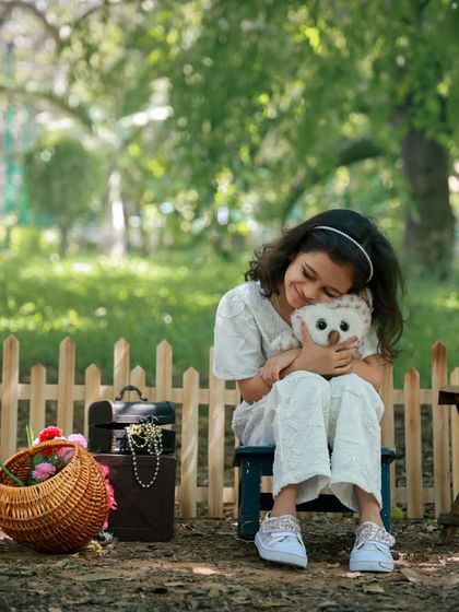 A sweet and tender moment as a young girl hugs her stuffed owl in a peaceful garden setting. We love capturing these quiet, candid interactions during our outdoor sessions.