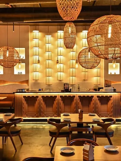 The bar area serves as a central feature, with a backlit wall of niches and an intricately carved wooden front. This space was designed not just for service, but as a visual anchor that enhances the overall aesthetic of the dining room.