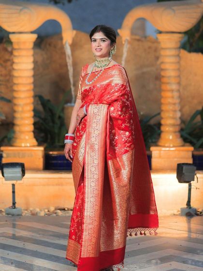 A full-length shot of the bride by a fountain. Her makeup is elegant and sophisticated, perfect for a grand reception.