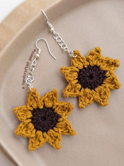 A clean product shot of the sunflower earrings, showing the detailed petals and dark center.