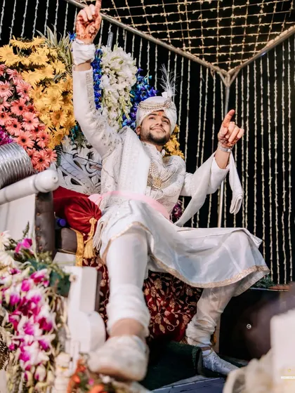 The groom, full of energy and joy, dances on his chariot during the Baraat procession.
