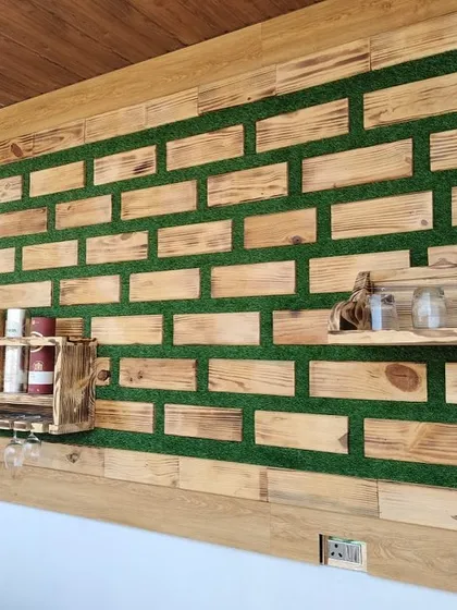 An angled shot of the custom wooden wall installation. This perspective shows the depth of the piece and how the different elements, like the bottle shelf and the smaller spice rack, are integrated into the overall design.