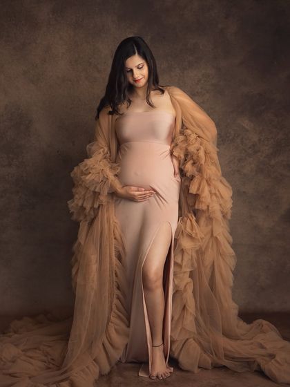 A quiet, downward glance at the baby bump speaks volumes. This pose is full of anticipation and love, beautifully framed by the soft fabric of the gown in my studio.