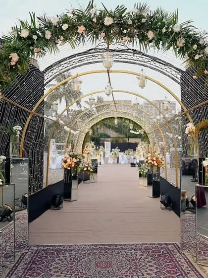 A dramatic and glamorous entrance tunnel with black floral arches and sparkling lights, leading to the main event area.