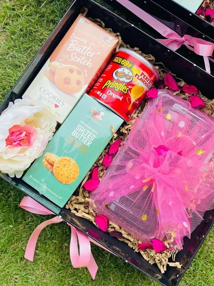 This custom Diwali hamper combines popular snacks like Pringles and butter cookies with a beautifully wrapped jar of sweets. The bright pink accents and flower details make it a cheerful gift for associates.