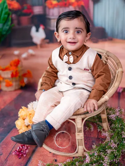 A sweet portrait in a wicker chair, this shot highlights his expressive eyes and cheerful personality against the colorful barnyard backdrop.
