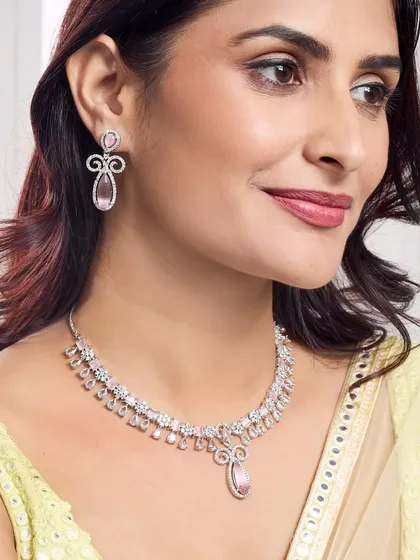 A close-up of a model wearing a delicate diamond and pink stone necklace set. The soft focus and gentle expression create a romantic feel, perfect for promoting gift collections.
