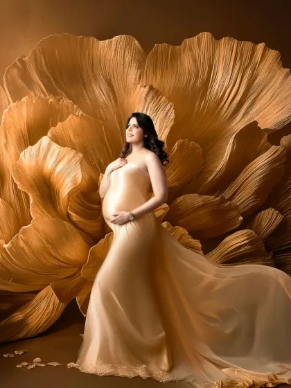 Blooming with life. In this unique portrait, the mother-to-be stands before a giant, handcrafted golden flower. Her shimmering gold gown and the artistic backdrop come together to create a truly one-of-a-kind, luxurious maternity photograph.