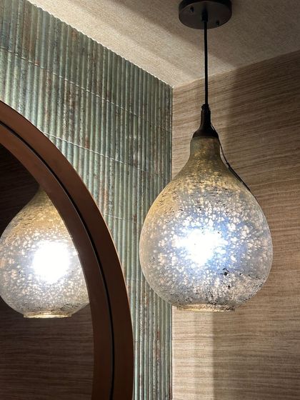 A close-up of a mercury glass pendant light, which adds a touch of sparkle and vintage charm to a modern bathroom.