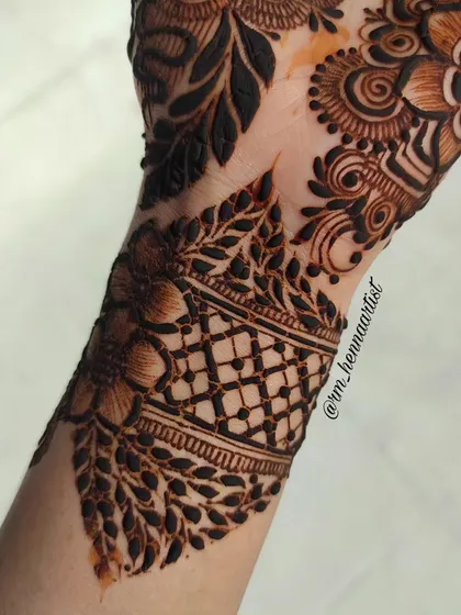A close-up of the wrist cuff. The grid pattern bordered by leaves adds a beautiful geometric touch to the floral design.