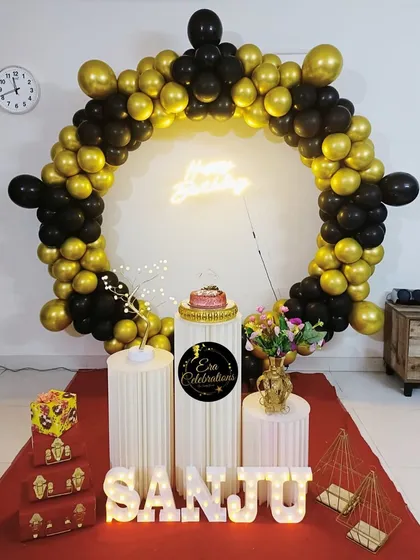 An elegant black and gold birthday theme. The circular balloon arch, neon sign, and white plinths create a very modern and sophisticated look.