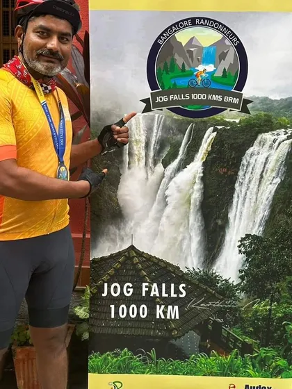 Pointing to the prize. A finisher proudly showcases the Jog Falls 1000K banner, a symbol of his hard-earned achievement.