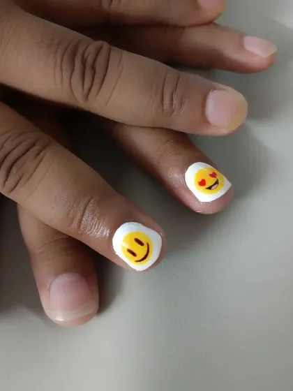 A simple and cute design featuring hand-painted emojis on short, natural nails.