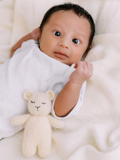 A curious, wide-eyed newborn with his little teddy bear. Even when babies don't sleep, we capture beautiful, alert expressions that are just as precious.