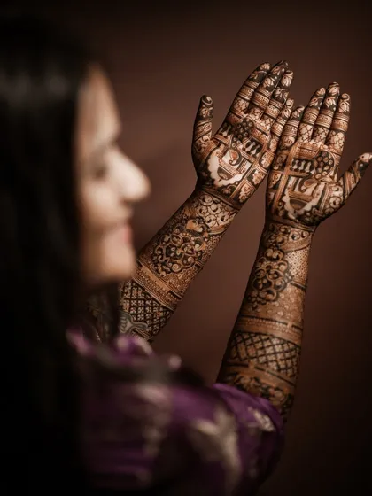 An over-the-shoulder shot of a client admiring her full-arm engagement mehndi.