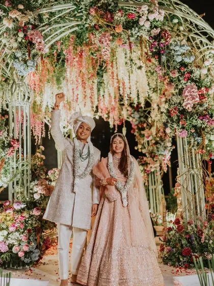 Pure joy after the ceremony! The couple stands under a magnificent floral arch, a perfect blend of traditional structure and modern, abundant floral design.