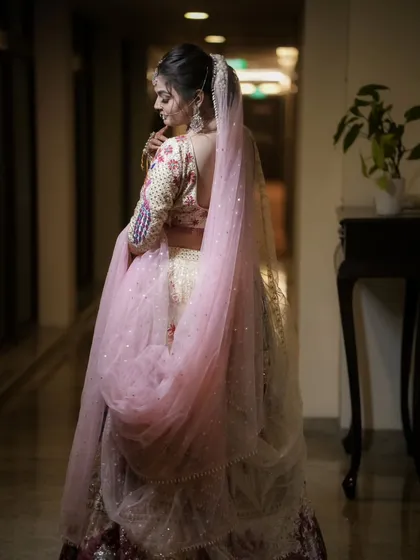 A beautiful shot from behind, highlighting the intricate details of the blouse and the delicate veil. This angle offers a unique and elegant perspective on the bridal look.
