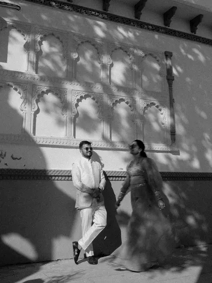 A playful and artistic black and white shot. The bride seems to be pulling the groom along, with the dramatic shadows adding a dynamic and creative element.