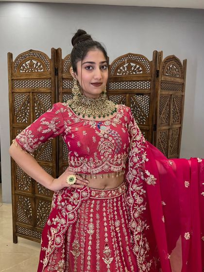 A close-up of the rani pink bridal lehenga's blouse. The detailed embroidery, featuring peacock motifs and delicate beadwork, shows the quality of this pre-loved designer piece.