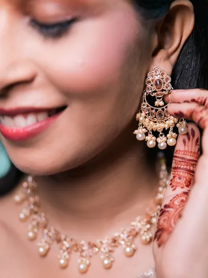 A close-up of the bride adjusting her beautiful pearl and gold earring, a key piece of her bridal jewelry set.