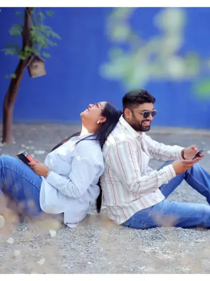 A relaxed and candid moment from a pre-wedding shoot. The couple is sitting back-to-back, lost in their own world, which makes for a very natural and authentic photograph.