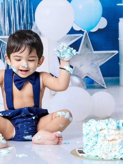 Dressed in a dapper bow tie and suspenders, this little gentleman is having a blast. The blue and white theme creates a classic and joyful setting for his cake smash.