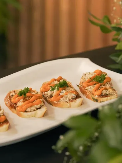 Four perfectly arranged bruschettas, topped with a savory filling and a drizzle of sauce. I focus on neat and attractive plating for all my canapés.