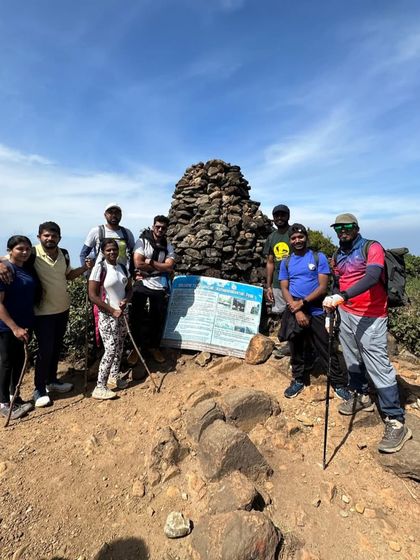 A small group at the Kumara Parvatha peak, marked by a pile of stones. The feeling of achievement is visible on their faces.