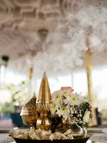 A centerpiece designed to cleanse the energy and invite positivity. The fragrant smoke from the incense cone rises from a traditional brass vessel, setting a spiritual and calming tone for the Bhajan Sandhya.